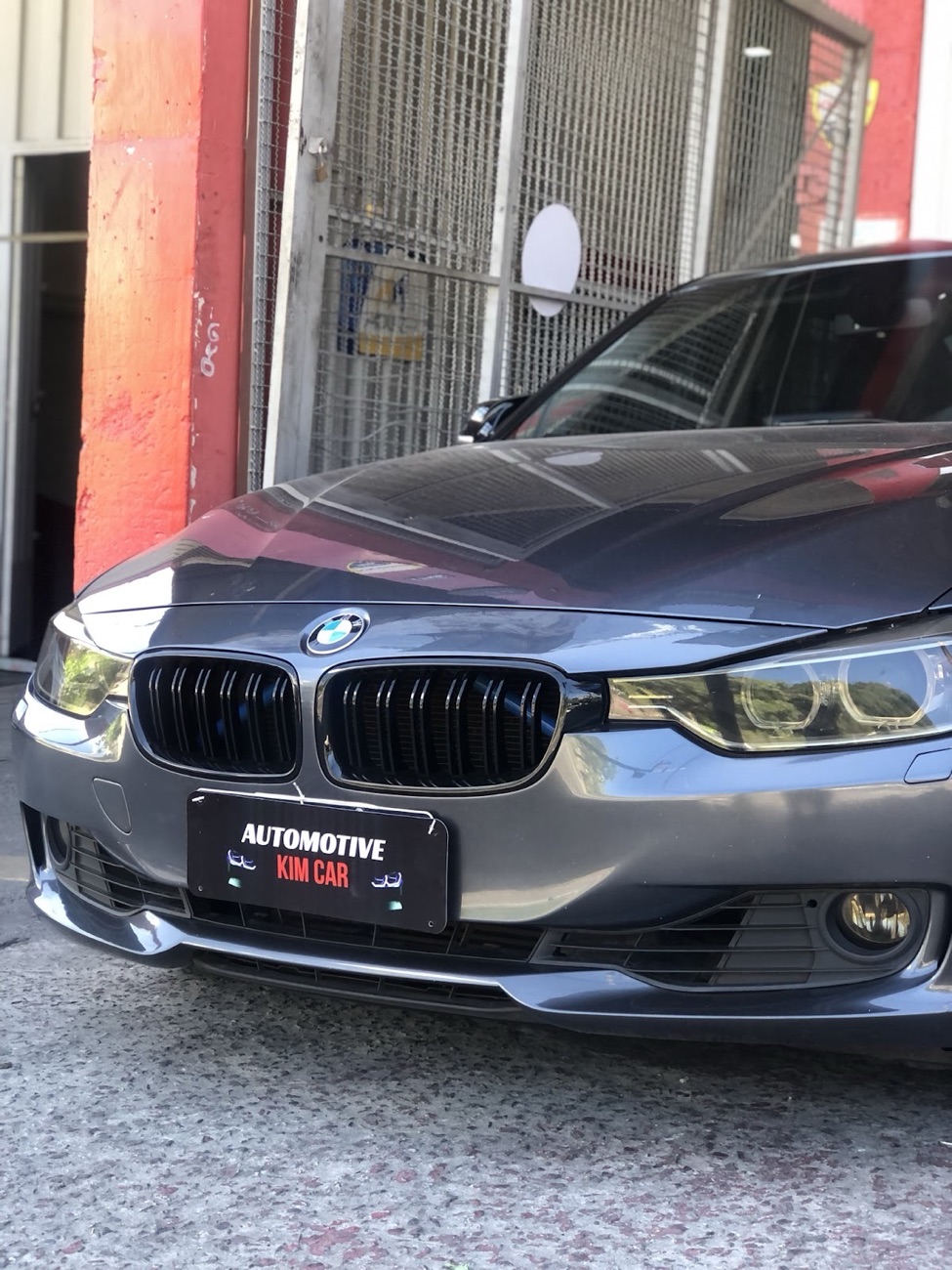 BMW com a placa da Automotive KimCar na frente da oficina